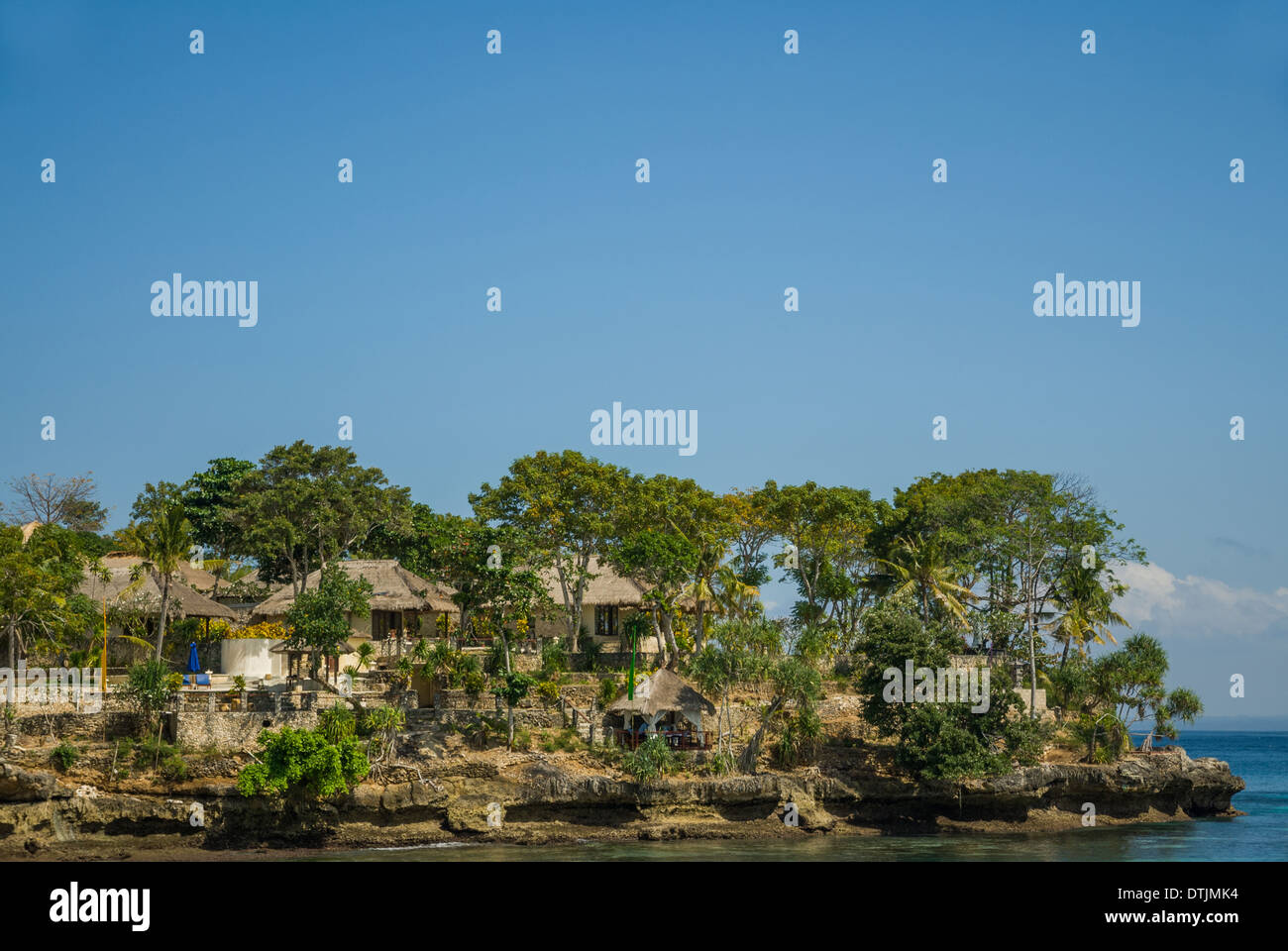 Resort sulla scogliera vicino le chiare acque blu del mare con le barche e gli alberi in un bel giorno chiaro Nusa Lembongan Thailandia Foto Stock