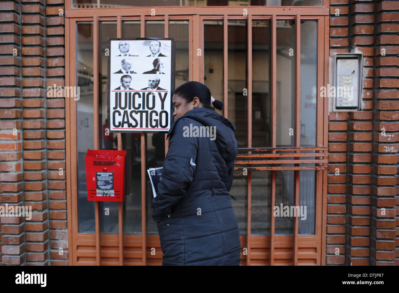 Madrid, Spagna. 19 feb 2014. 29 anno-ol Maria Menendez Melendez entra attraverso la porta della sua casa dove un banner con le facce delle principali banche spagnole viene visualizzato ed è scritto " Trial e punizione'' dopo sapendo che lei lo sfratto è stato rinviato senza data di Madrid in Spagna, mercoledì, 19 febbraio 2014. Maria Menendez Melendez 29 anni da Repubblica Dominicana ha vissuto per otto anni con il suo compagno Carlos e i loro due bambini, Raquel ConcepciÃƒÂ³n Menendez 9 anno-vecchio e Jean Carlos Concepcion Menendez 6 anno-vecchio, in un appartamento di proprietà di ''La camma -Sabadell'' w Foto Stock