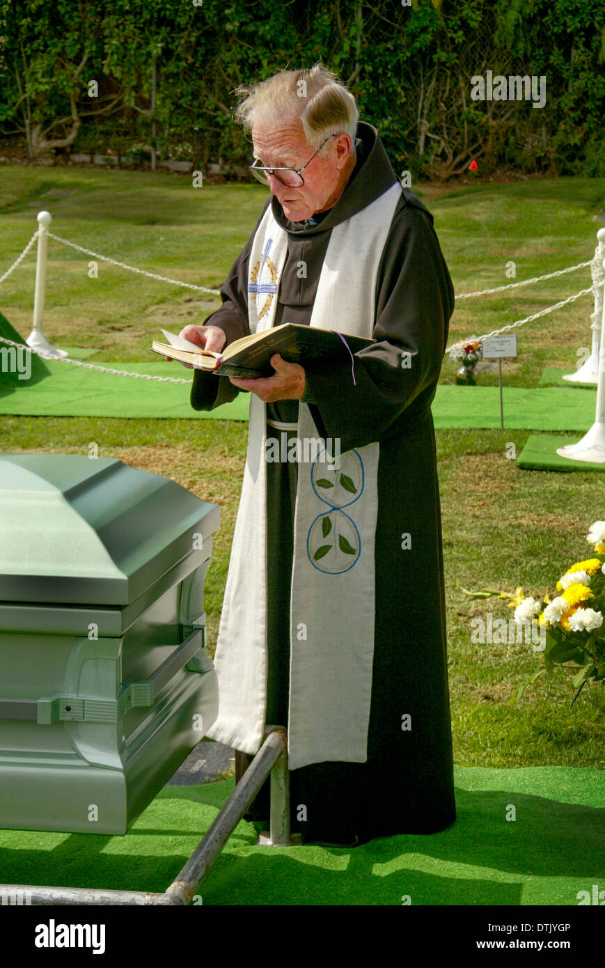 Un vestito sacerdote francescano officiates in corrispondenza di una sepoltura a Santa Barbara, CA. Nota scrigno. Foto Stock