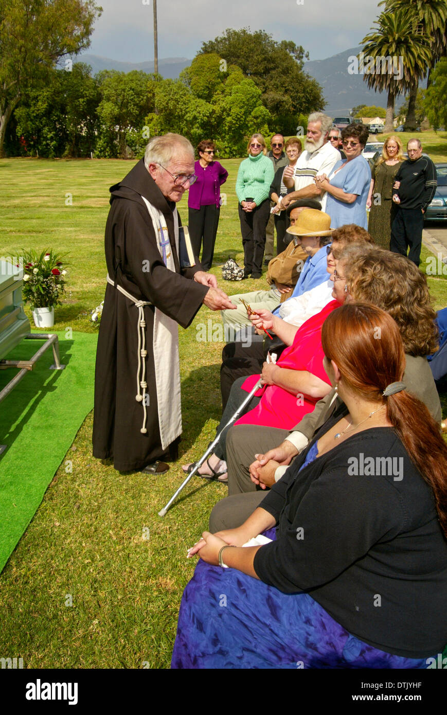 Un vestito sacerdote francescano parla con i membri della famiglia Dopo officiating a una sepoltura a Santa Barbara, CA. Foto Stock