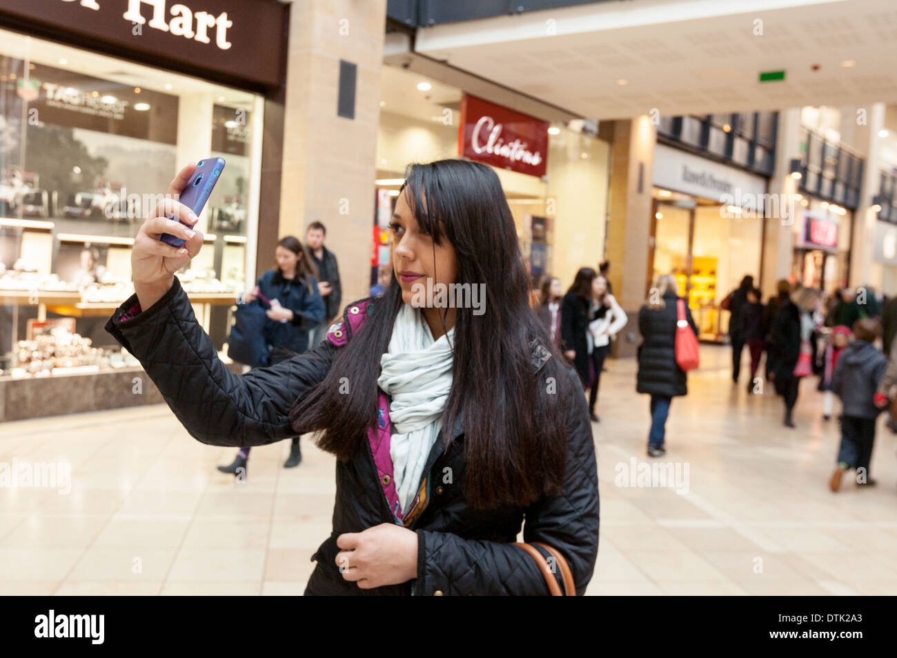 Giovane donna prendendo un selfie foto sul suo telefono cellulare in un centro commerciale per lo shopping, Cambridge Regno Unito Foto Stock