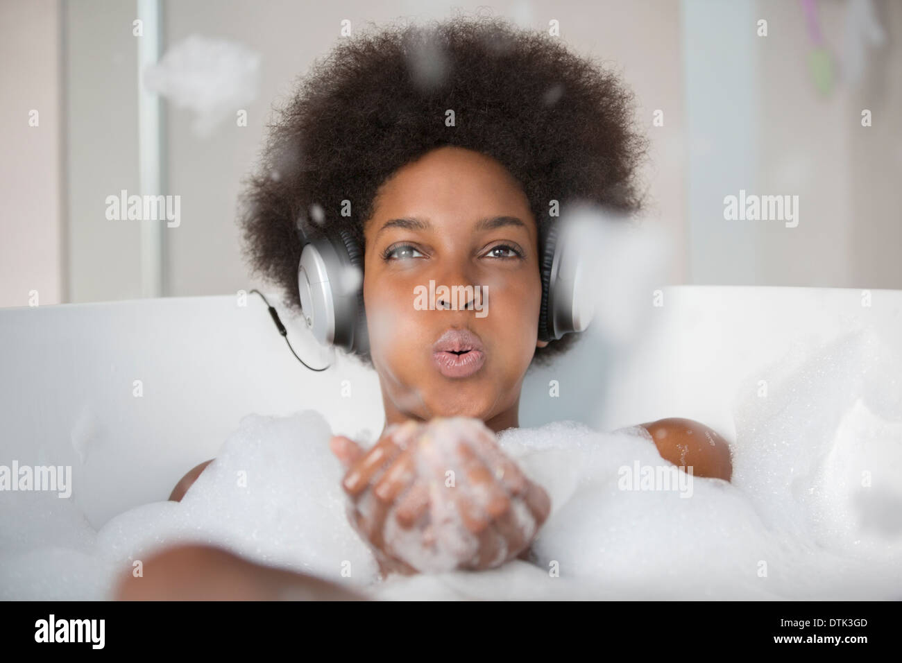 Donna ascoltando le cuffie nella vasca da bagno Foto Stock