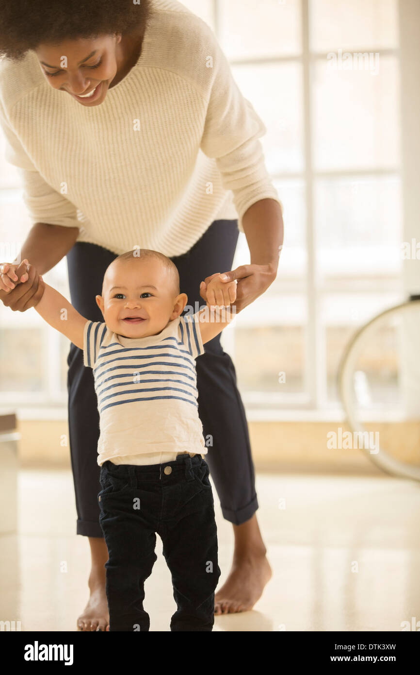 Madre aiutare baby boy a piedi sul pavimento Foto Stock