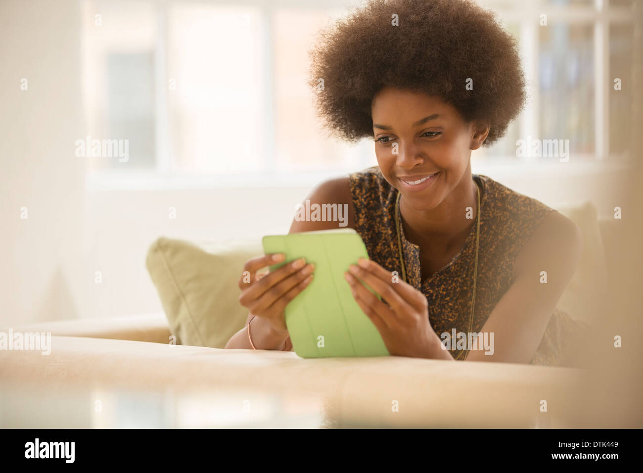 Donna con tavoletta digitale sul divano Foto Stock