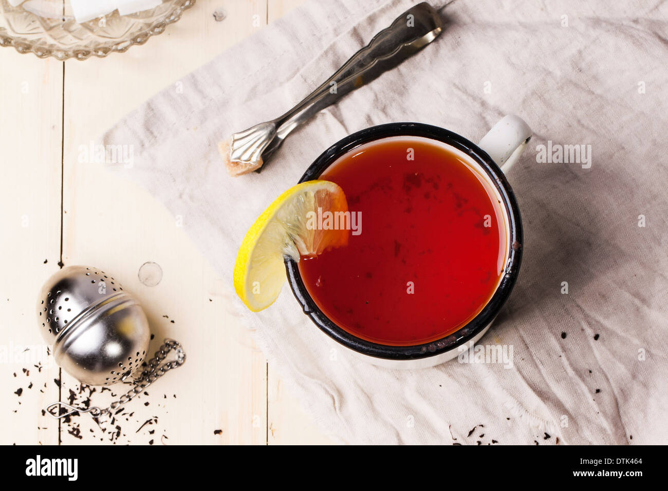 Vista dall'alto su vintage white tazza di tè con limone, servito con filtro di tè e zucchero-pinze su bianco tavolo in legno Foto Stock