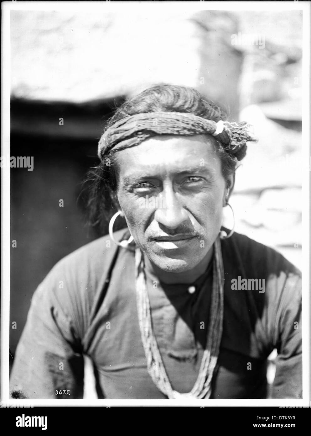 Ritratto di Indiano Navajo uomo guerriero che indossa il copricapo, orecchini in argento e collana wampum, ca.1900 Foto Stock