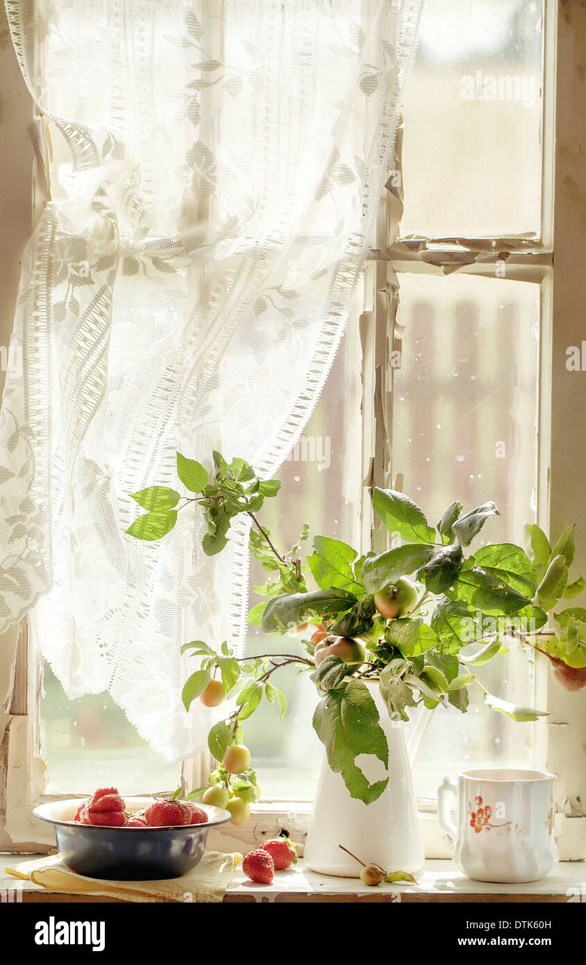 Bouquet da rami di mela e susina alberi e una ciotola di fragole su un vecchio davanzale Foto Stock