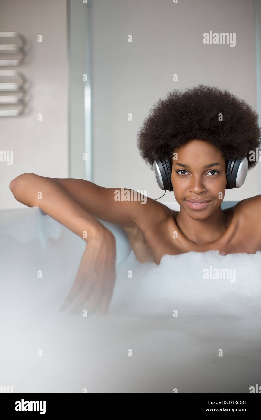 Donna ascoltando le cuffie nella vasca da bagno Foto Stock