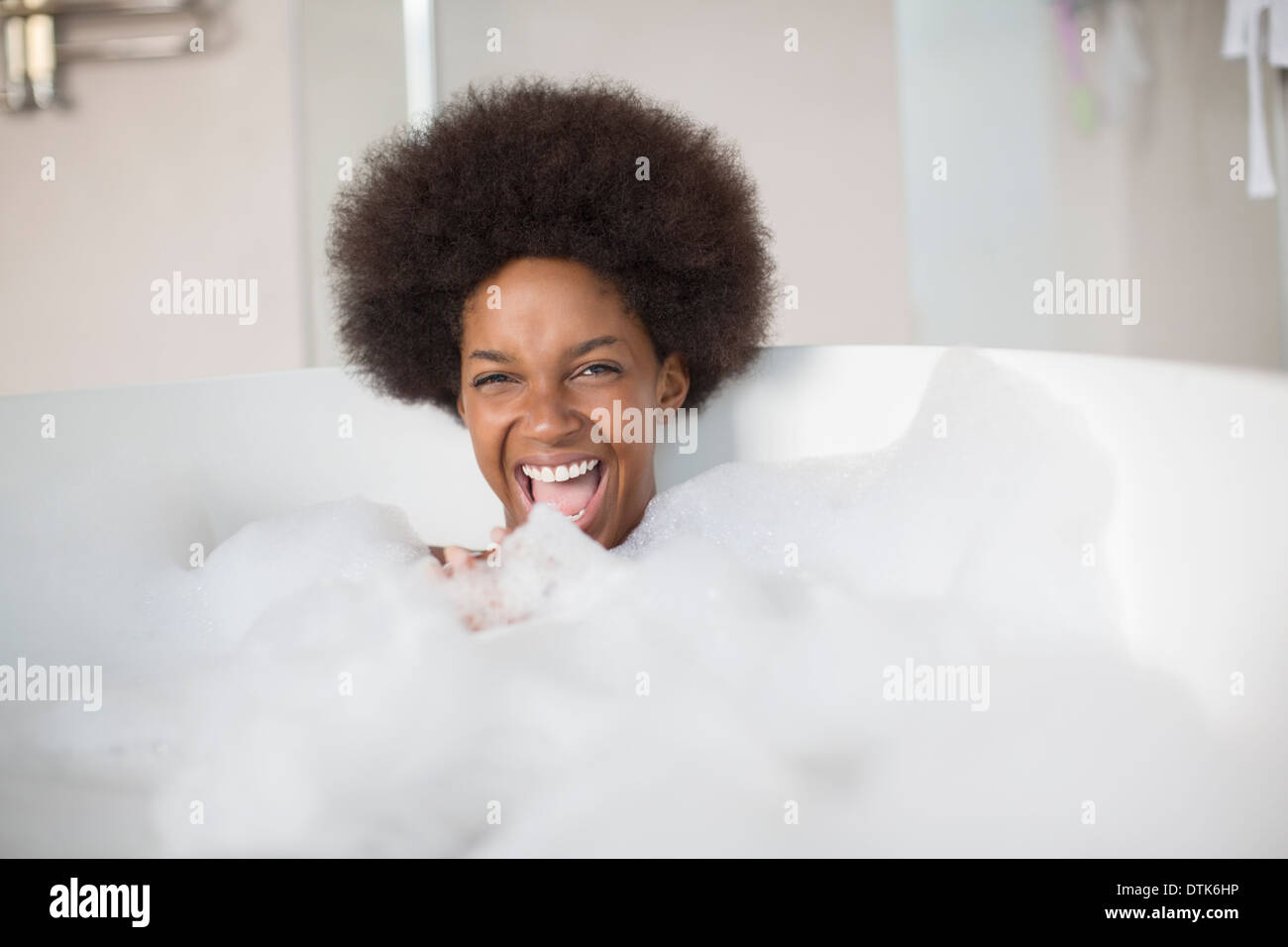 Donna che ride in bagno di bolle Foto Stock