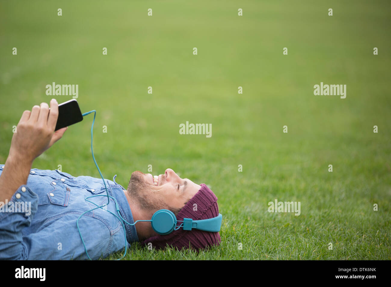 Uomo che ascolta le cuffie sul prato Foto Stock