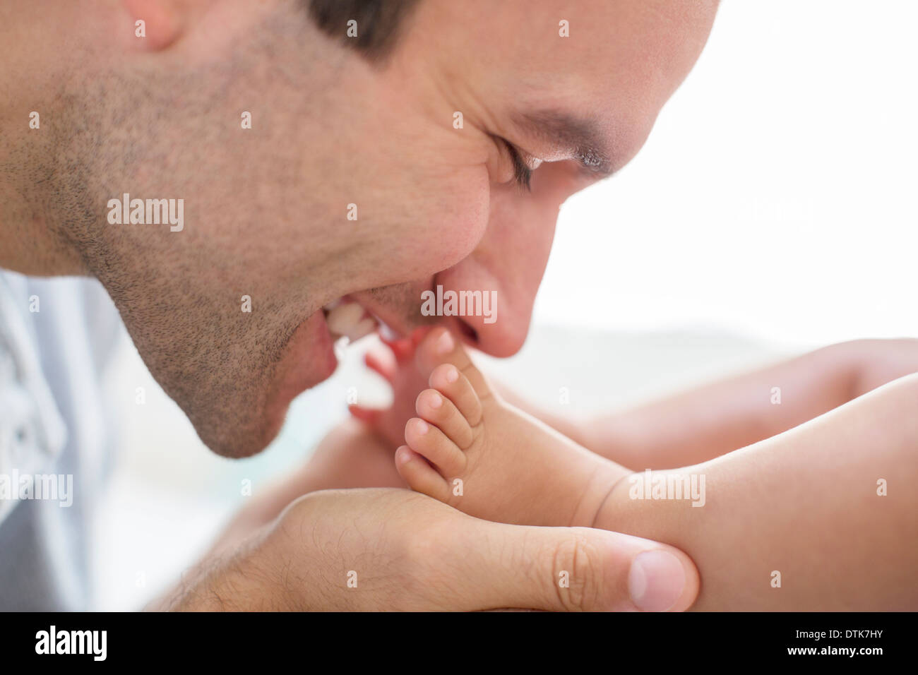 Padre kissing baby boy i piedi Foto Stock