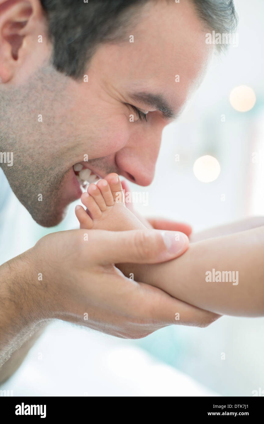 Padre kissing baby boy i piedi Foto Stock
