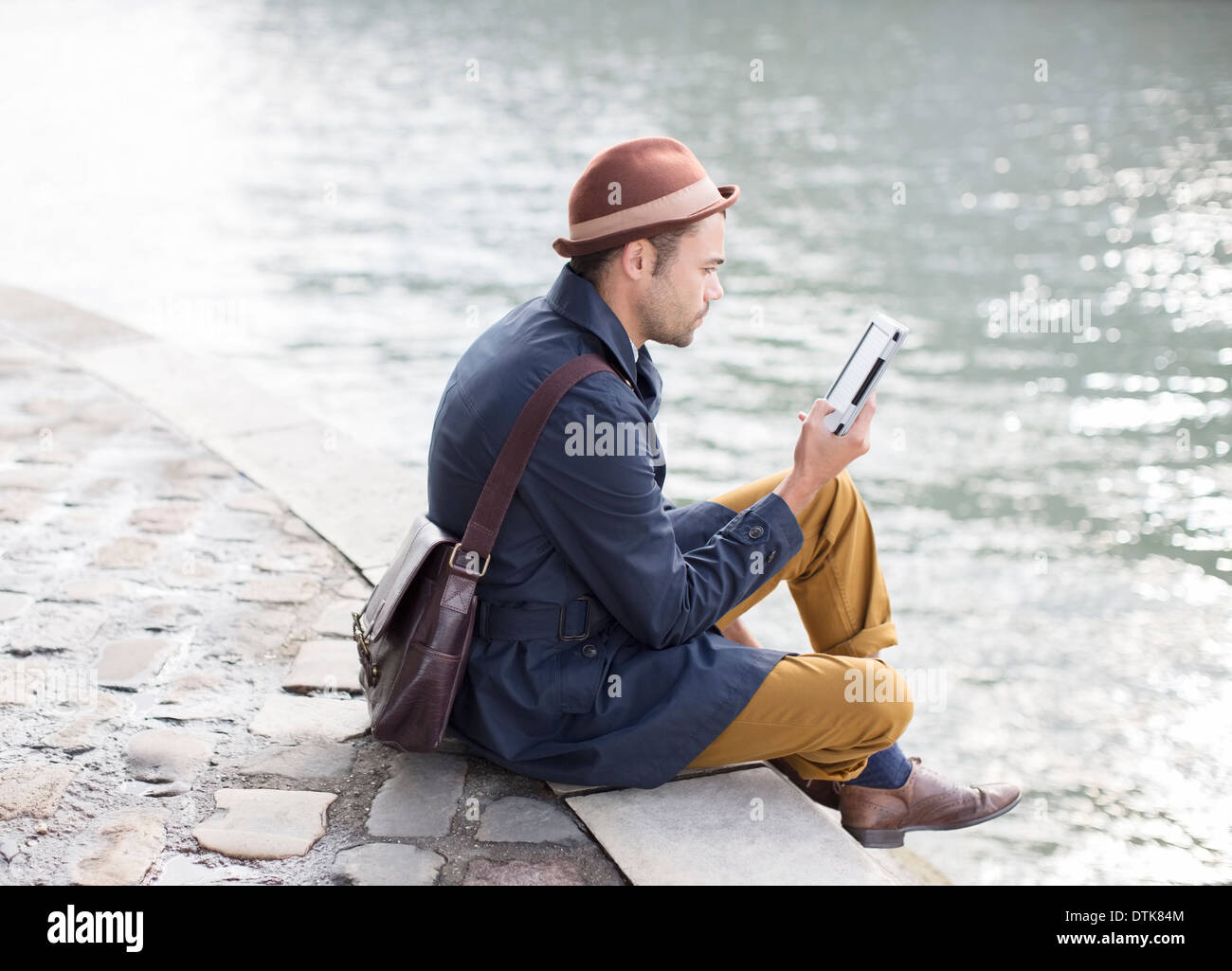 Uomo con tavoletta digitale lungo il fiume Foto Stock