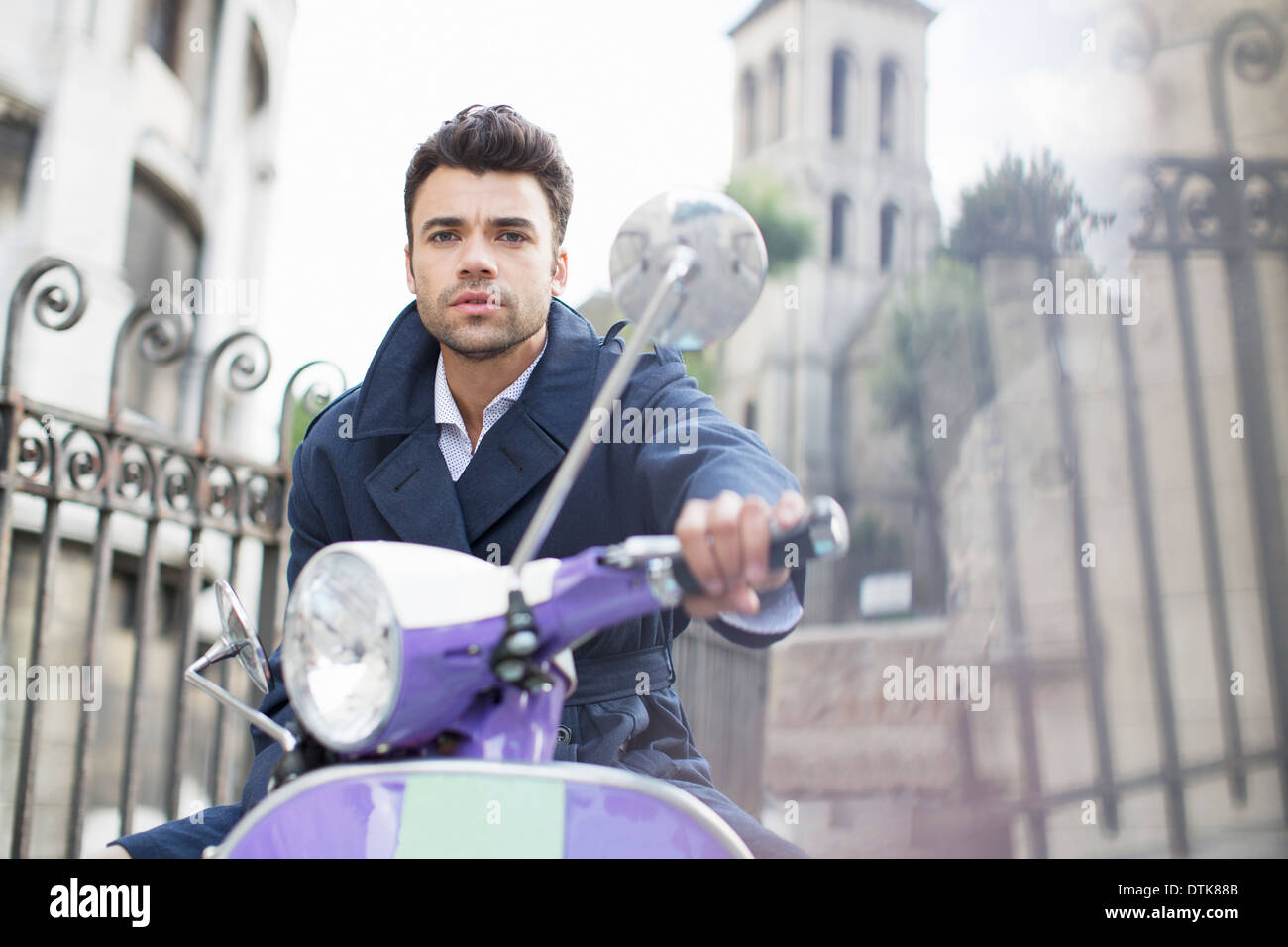 Uomo alla guida di uno scooter su strada di città Foto Stock