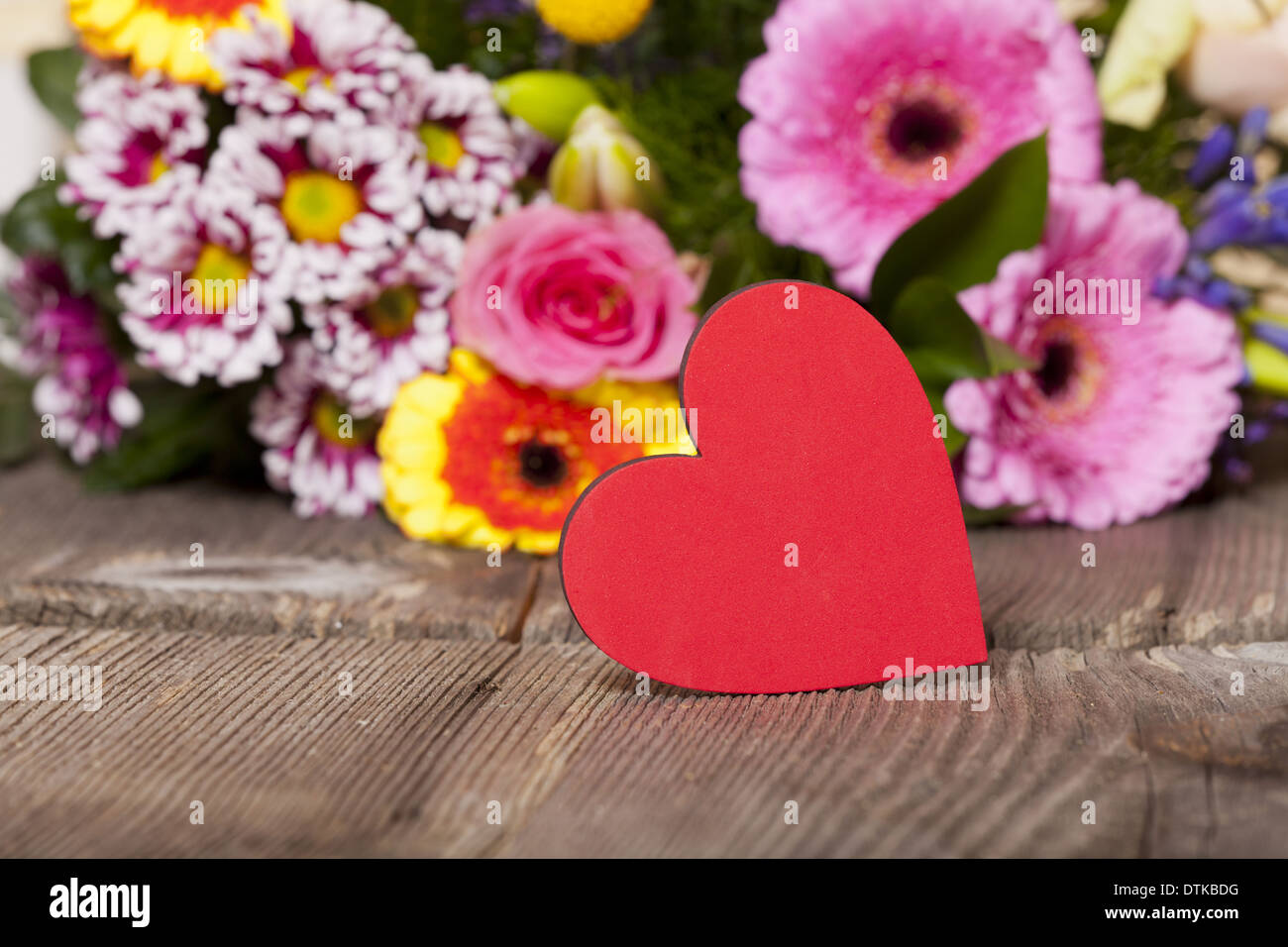 Saluti di fiori con un cuore rosso come simbolo nella parte anteriore di un  bouquet di