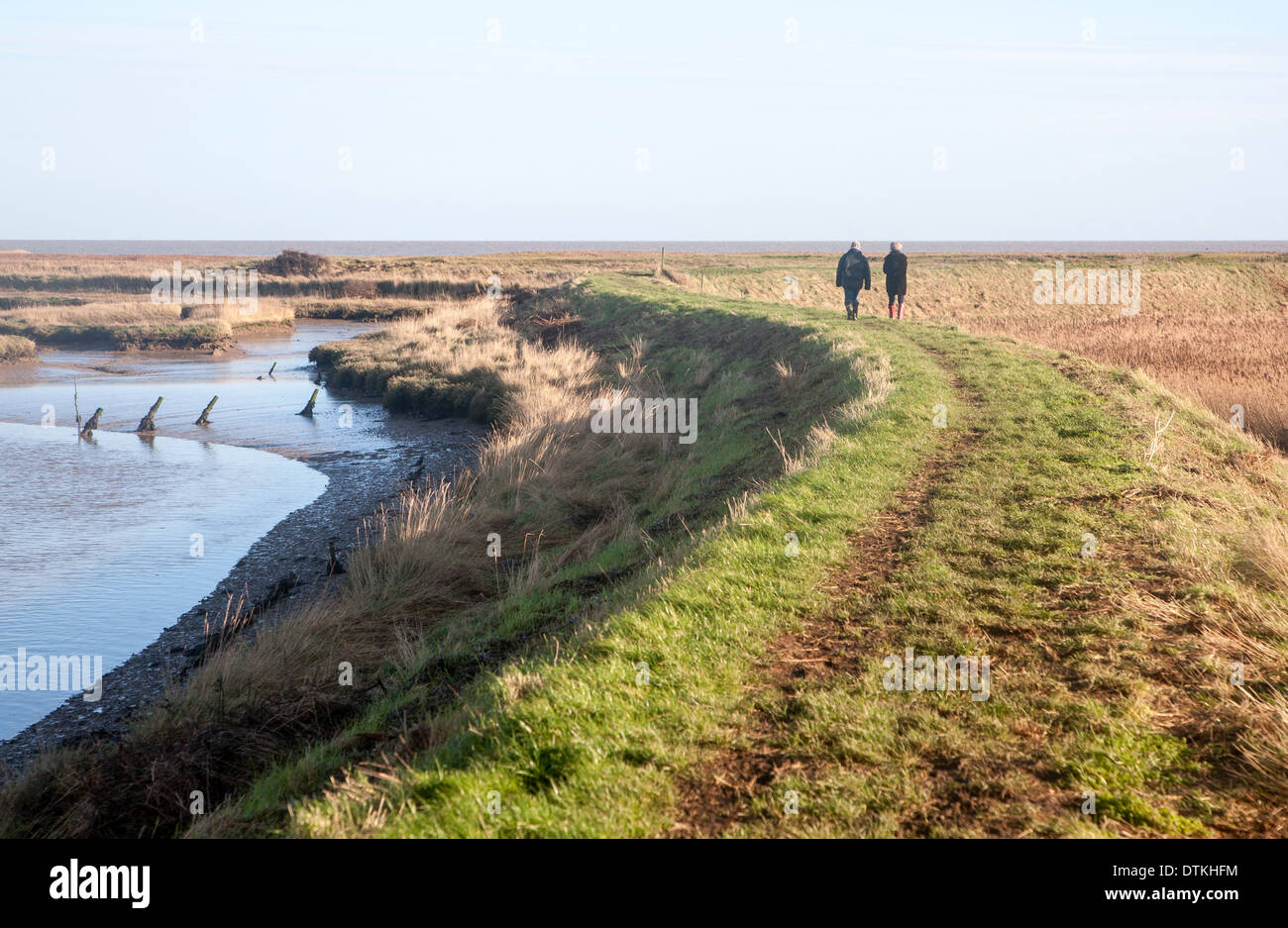 Due persone che camminano sulla difesa costiera di parete in corrispondenza di strada di ciottoli, Suffolk, Inghilterra Foto Stock
