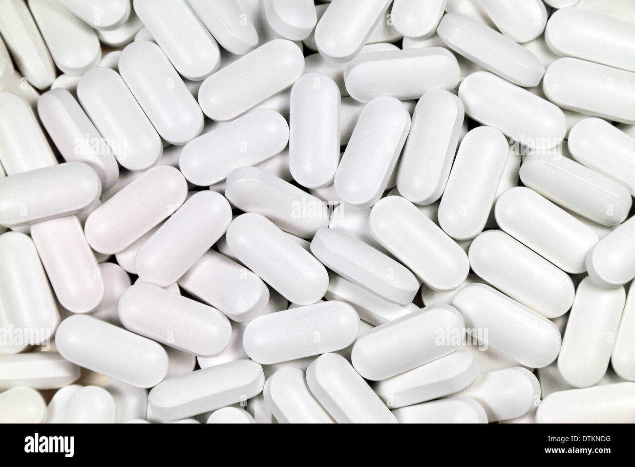 Pila di capsula bianca tipo pillole su uno sfondo luminoso. Foto Stock