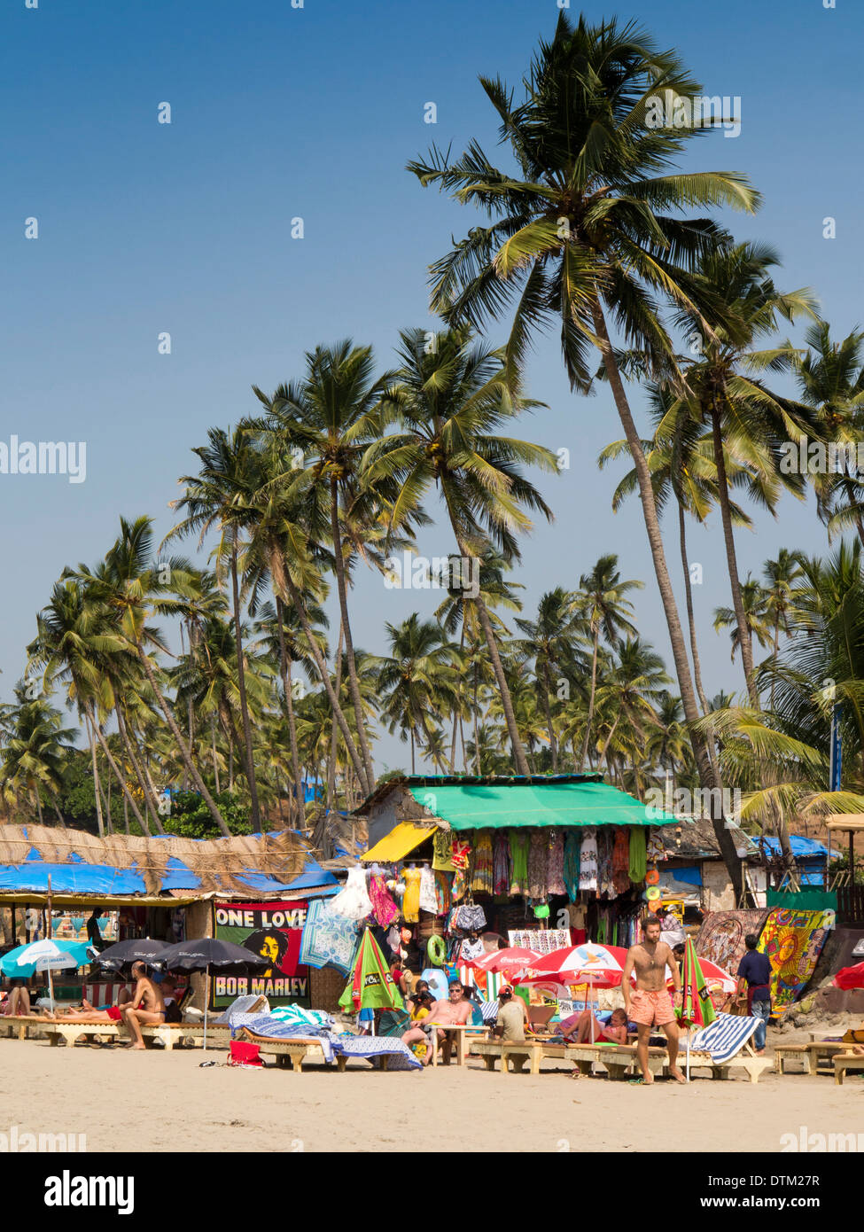 India, Goa, Big Vagator beach, turistico russo sulle sedie a sdraio a barre qui sotto alte palme di cocco Foto Stock