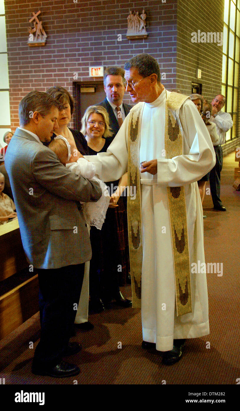 Vestita di un sacerdote cattolico saluta i genitori e i bambini durante le cerimonie di battesimo in una chiesa a Irvine, CA. Foto Stock