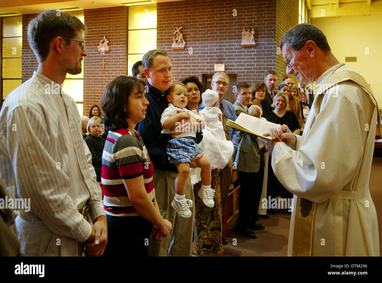 Vestita di un sacerdote cattolico legge un sermone per genitori e bambini durante le cerimonie di battesimo in una chiesa a Irvine, CA. Foto Stock