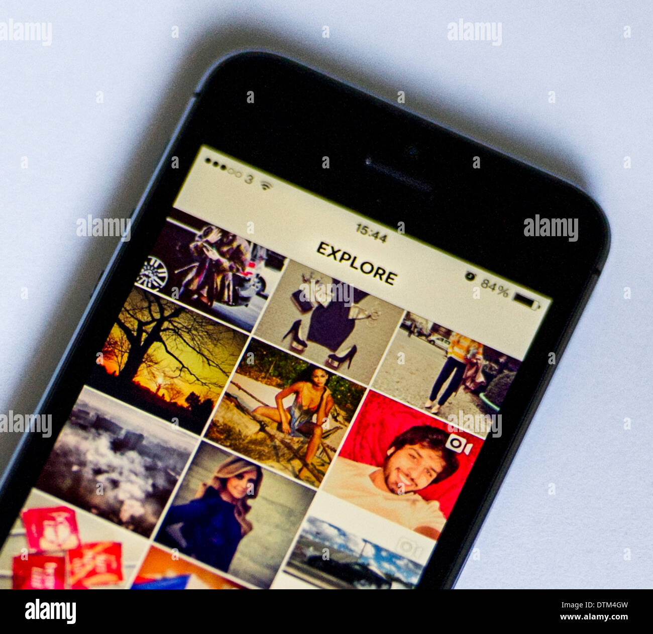 Un iPhone 5S su uno sfondo bianco, che mostra la pagina di esplorazione della Instagram app, che mostra alcuni dei più popolari le foto. Foto Stock