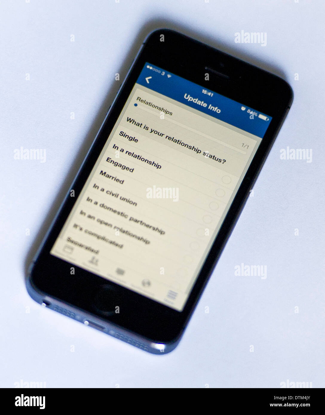 Un iPhone 5S su uno sfondo bianco, che mostra le app Facebook per chiedere all'utente del rapporto di stato. Foto Stock