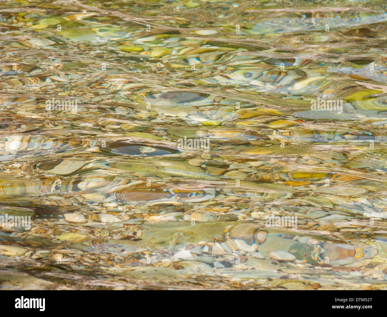 Calma acqua poco profonda distorce i ciottoli su una spiaggia Foto Stock