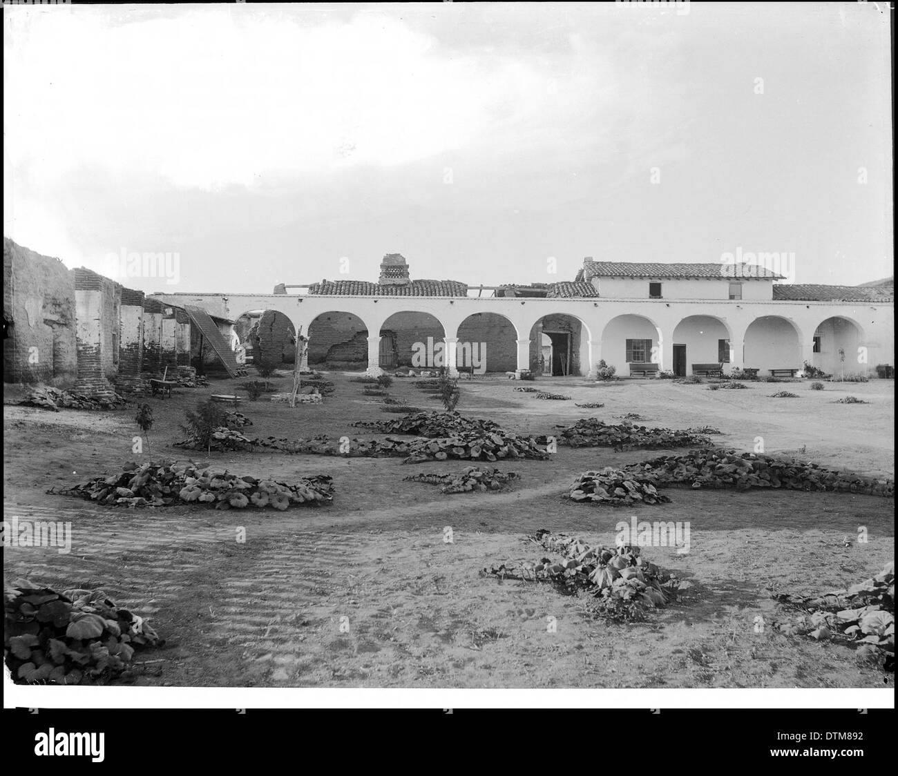 Questa fotografia fornisce una vista del quadrilatero della missione San Juan Capistrano nella Contea di Orange, California, scattata intorno al 1900. Mostra l'architettura storica e il cortile aperto della missione. Foto Stock