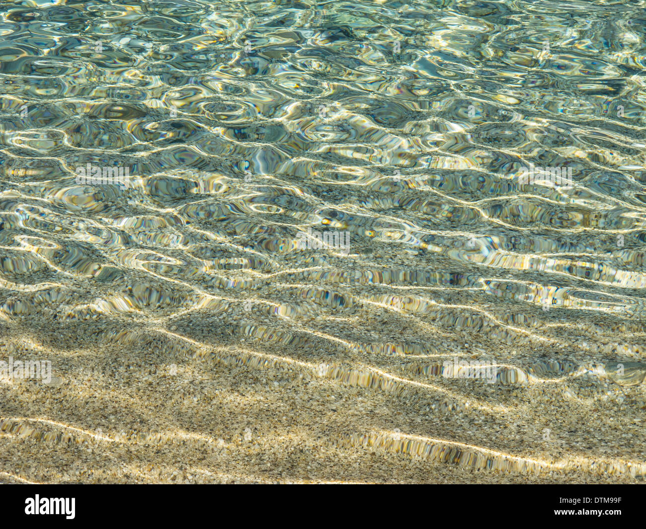 Calma acqua poco profonda distorce i ciottoli su una spiaggia Foto Stock