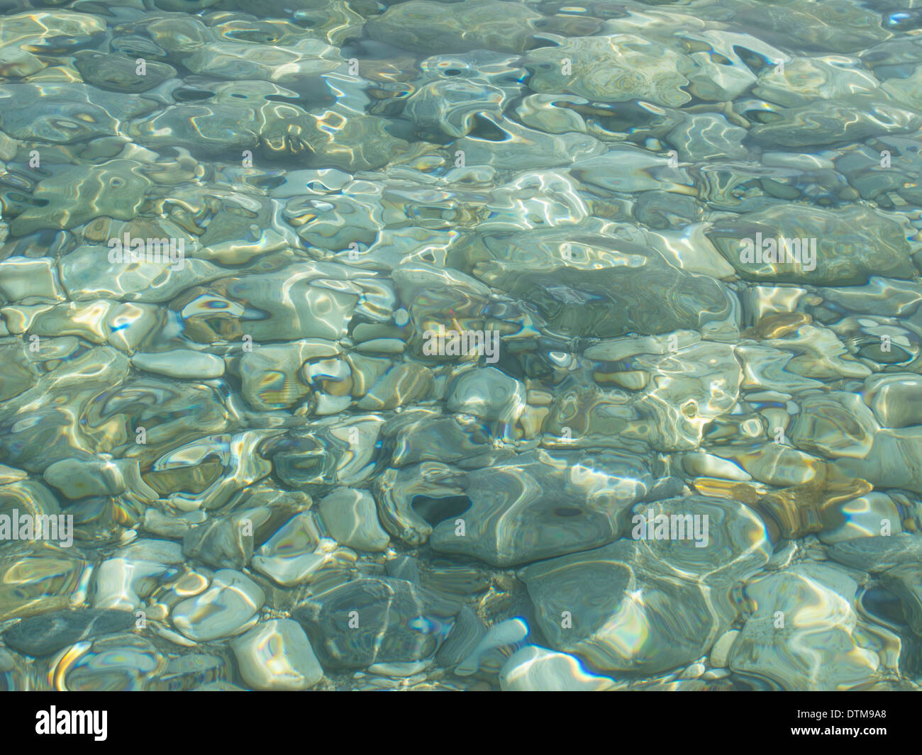 Calma acqua poco profonda distorce i ciottoli su una spiaggia Foto Stock