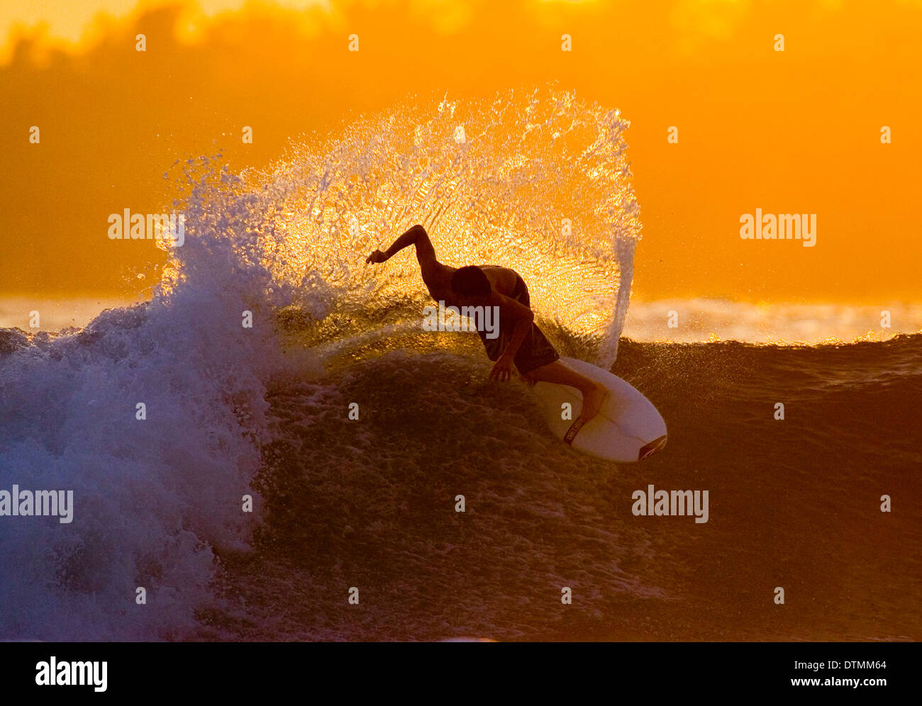 Surfer su una tavola da surf a cavallo di un onda nel mare oceano onda acqua beach capovolgere e fare trucchi in una muta e boardshorts Foto Stock