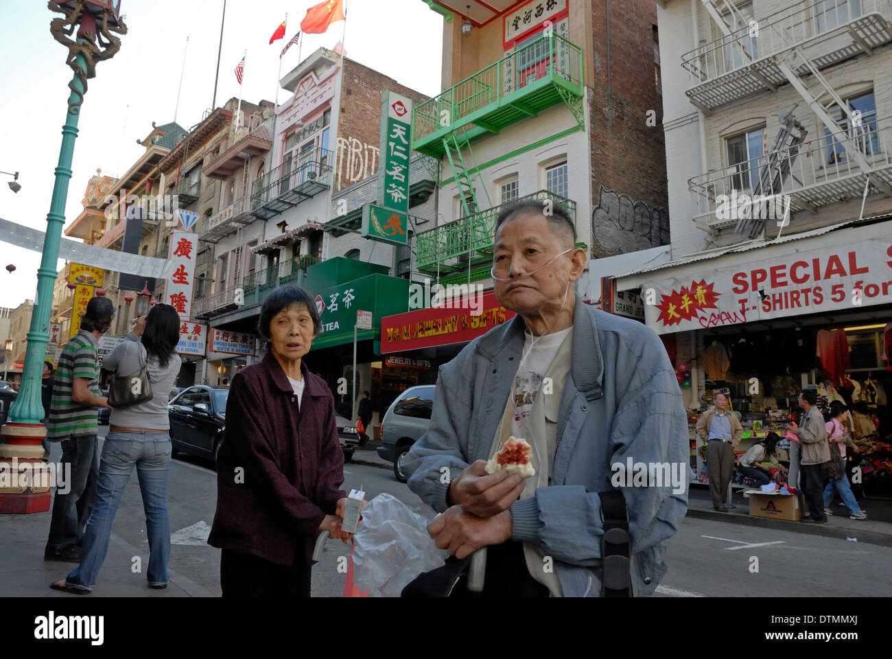 Uomo cinese, su ossigeno, mangiare un dolce in attesa ad una fermata di autobus di Chinatown di San Francisco, California. Foto Stock