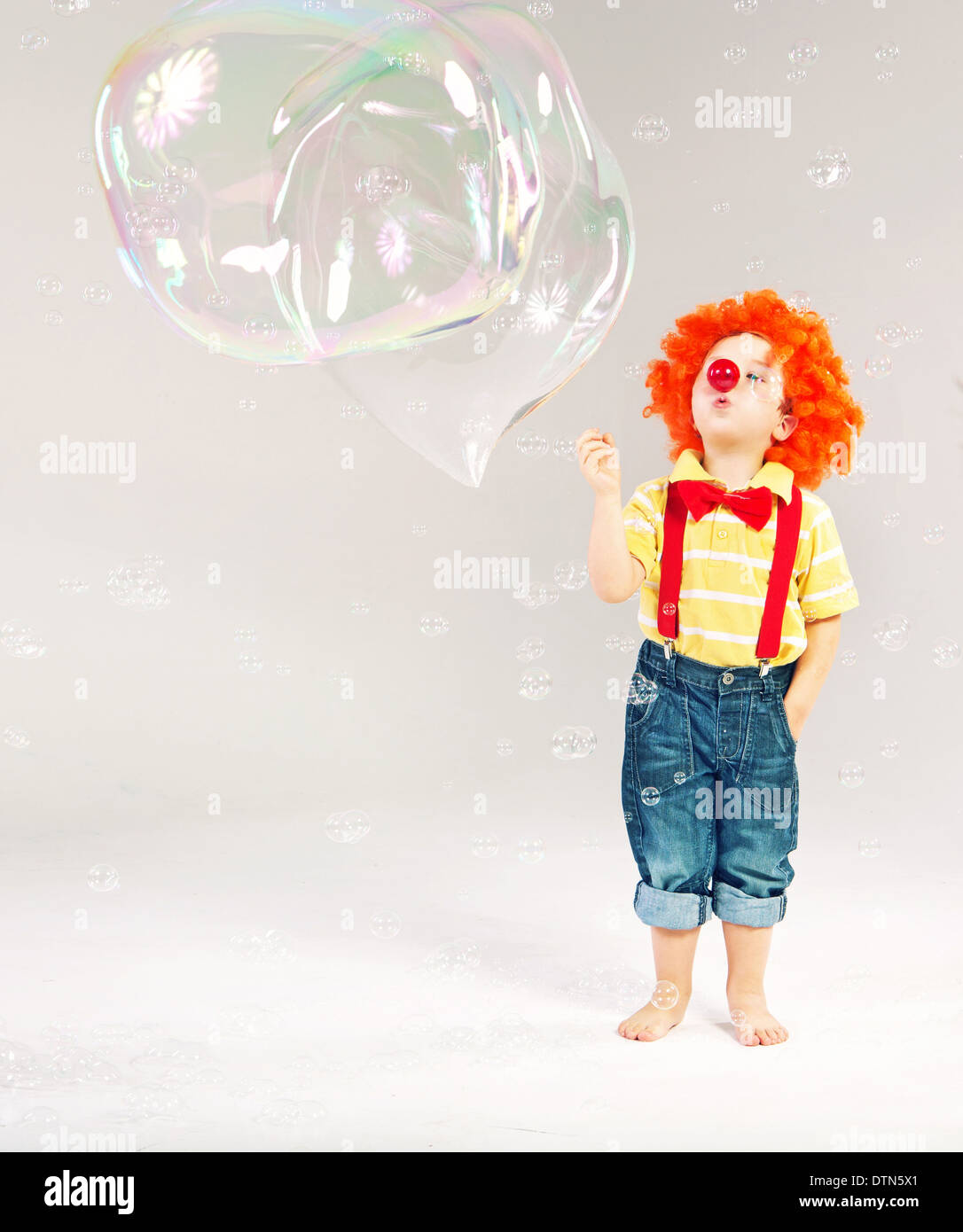 Divertente immagine del piccolo clown compiendo enormi bolle di sapone Foto Stock