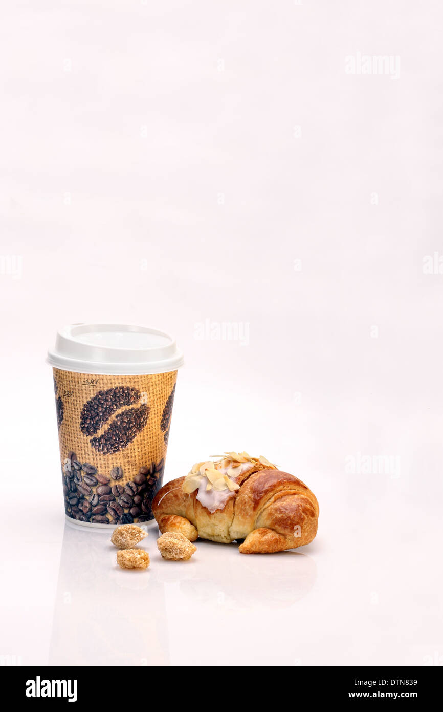 Caffè in tazza monouso e croissant con pasta di mandorle e zucchero di canna cubi Foto Stock