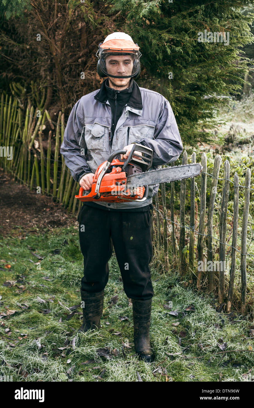Ritratto di professionale giardiniere con chainsaw in piedi nel giardino. Foto Stock
