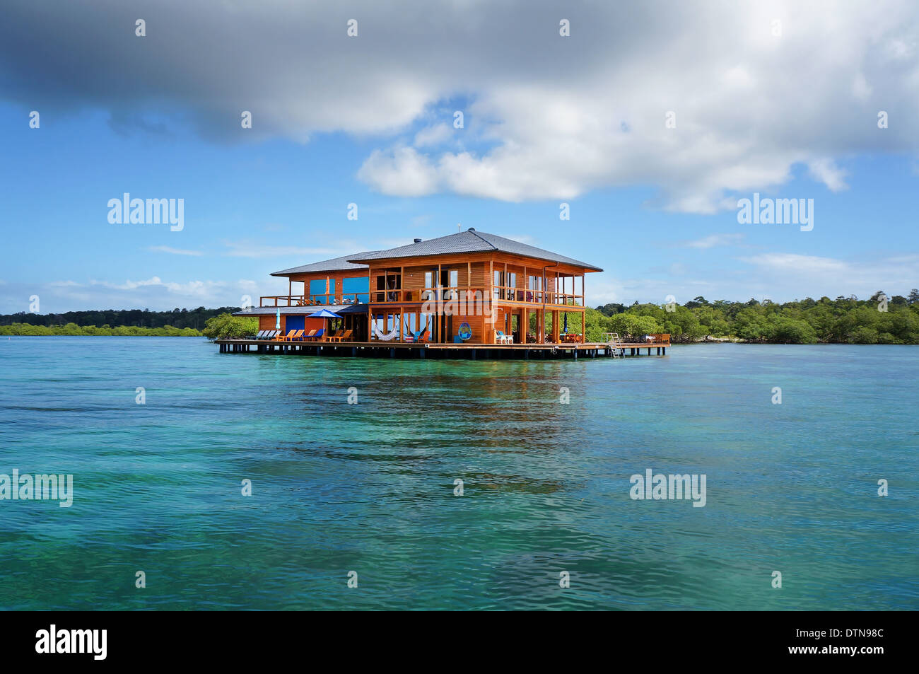 Bella casa su palafitte sopra l'acqua del mare dei Caraibi con nuvoloso cielo blu, Bocas del Toro, Panama Foto Stock
