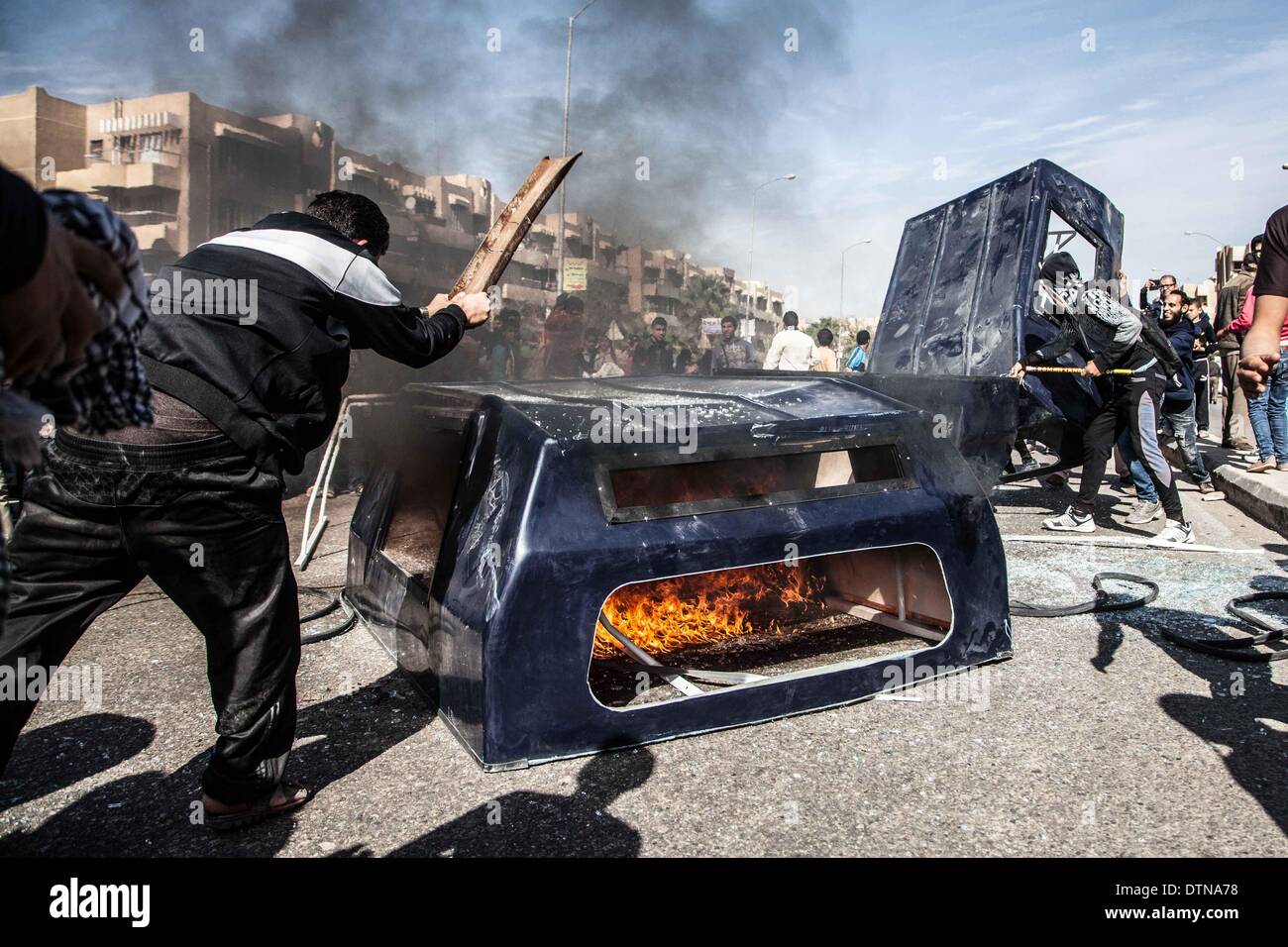 Il Cairo, Egitto. Il 21 febbraio, 2014. La gente ha colpito un veicolo della polizia che è impostato sul fuoco da anti-militari di manifestanti in 6 di ottobre la città, circa quaranta chilometri a ovest del Cairo, capitale dell Egitto, nel febbraio 21, 2014. Credito: Mosab Gamal/Xinhua/Alamy Live News Foto Stock