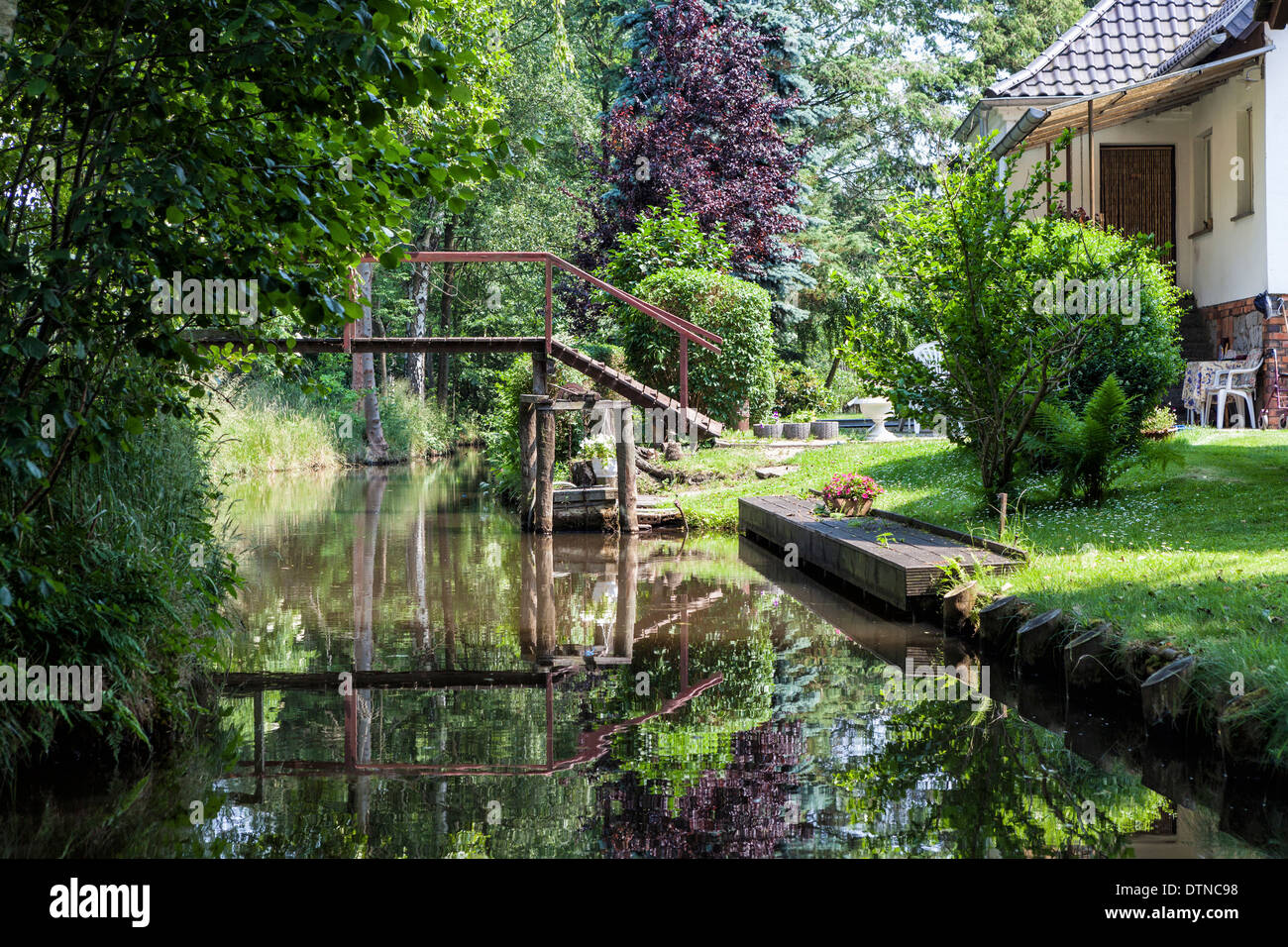 Casa con piedi ponte sulla rive del canale di irrigazione in Spreewald riserva della biosfera, Brandeburgo, Germania Foto Stock