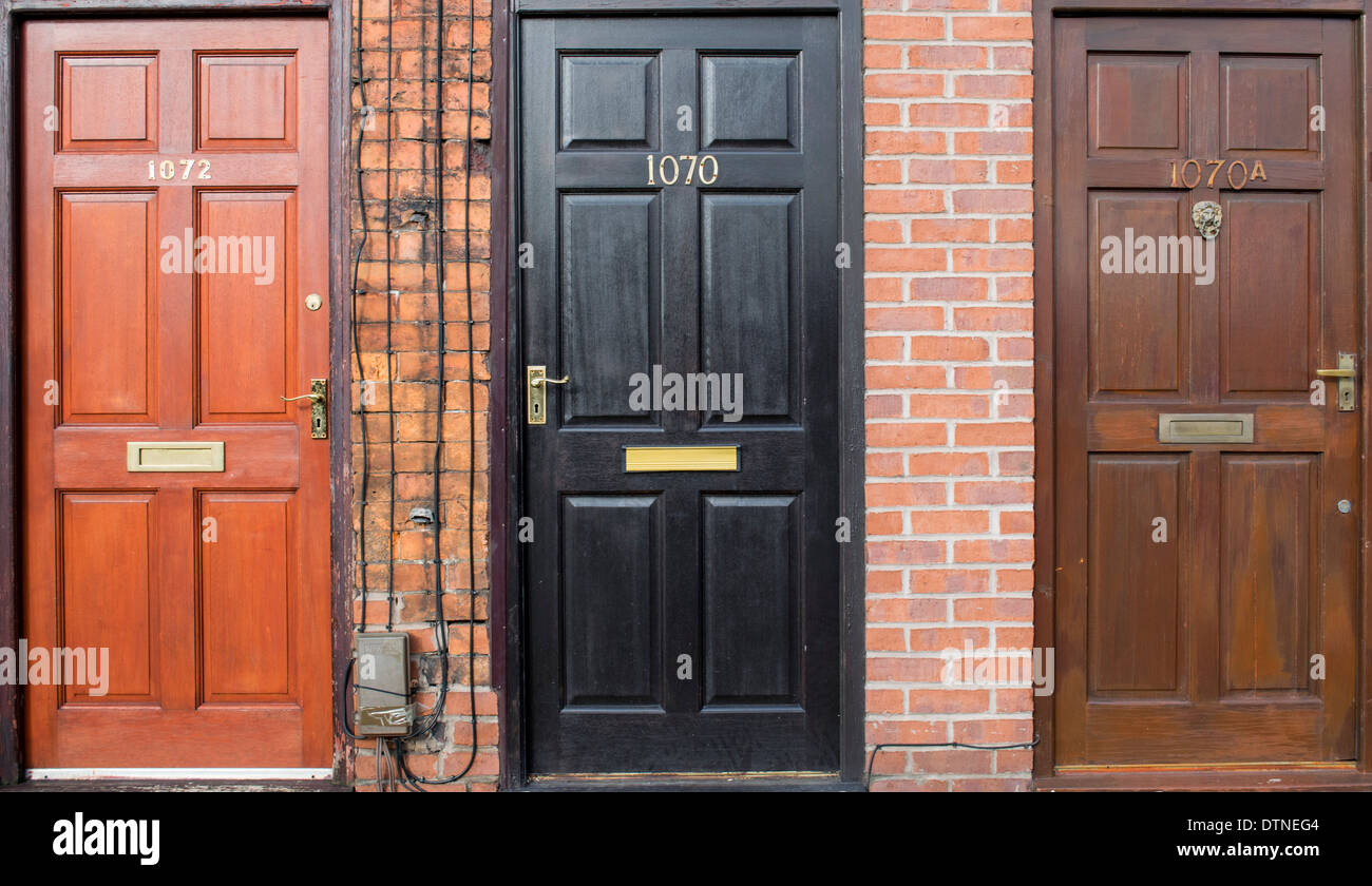 Tre porte anteriori su una fila di appartamenti e case a Manchester in Inghilterra, Regno Unito Foto Stock