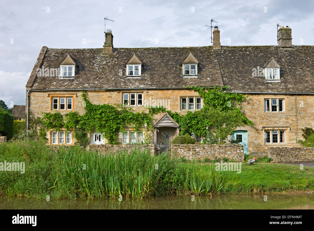 Cottage accanto al fiume occhio in Cotswolds village di Lower Slaughter, Gloucestershire, Inghilterra. Foto Stock