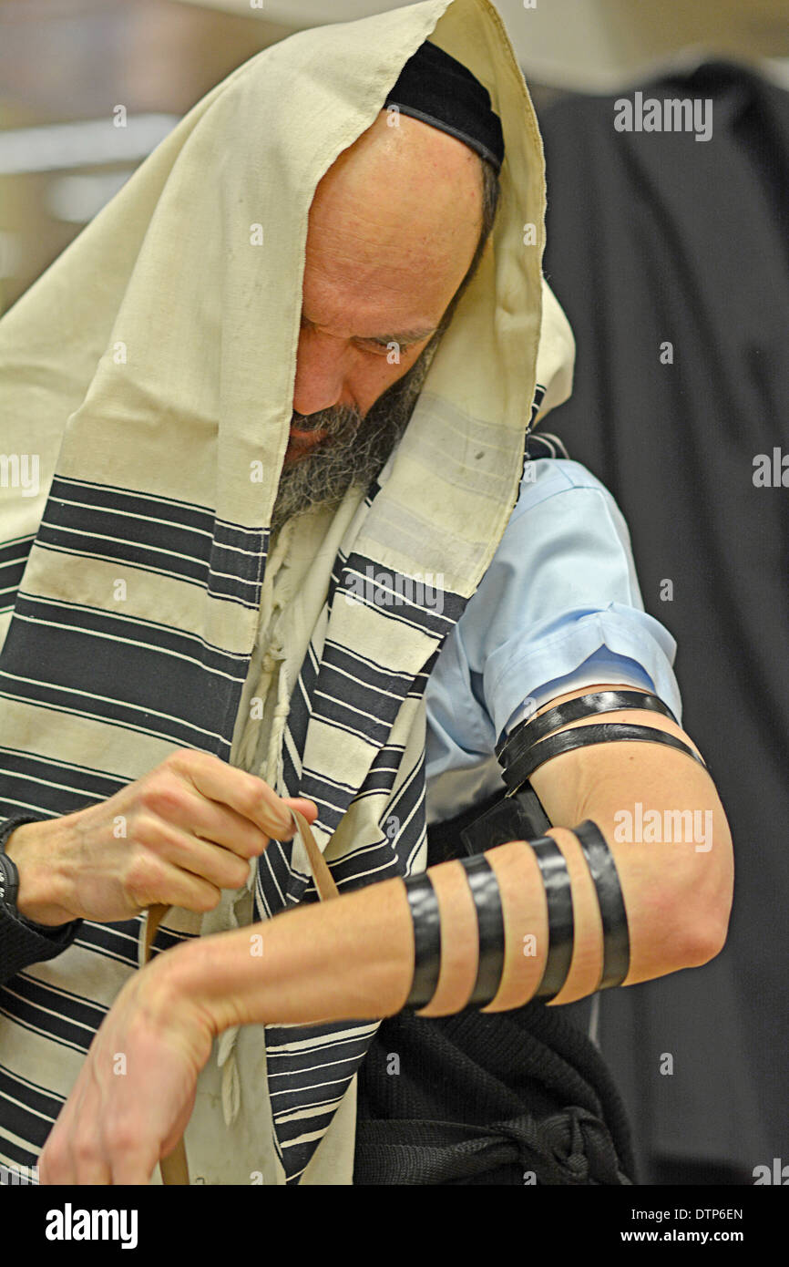 Religiosa ebraica uomo a mettere su phylacteries, teffilin, al mattino i servizi a una sinagoga di Brooklyn, New York. Foto Stock