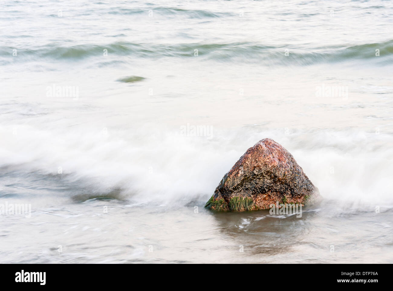 Singola pietra o roccia in un mare sfocato Foto Stock