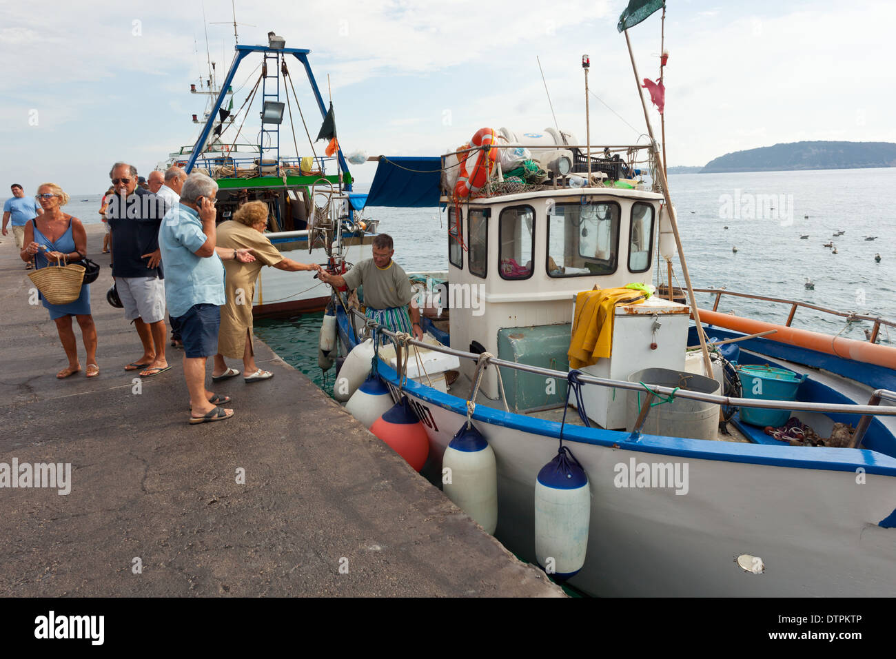 I turisti e gli operatori l'acquisto di pesce dalle barche da pesca. Isola d Ischia, Italia Foto Stock