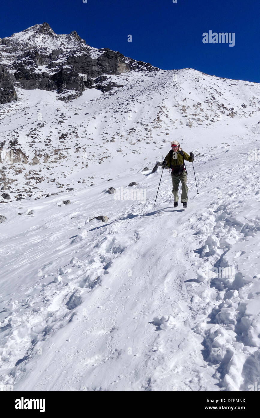 Trekker glassading giù dalla Larkya La (Larkya Pass) nella regione di Manaslu del Nepal. Foto Stock