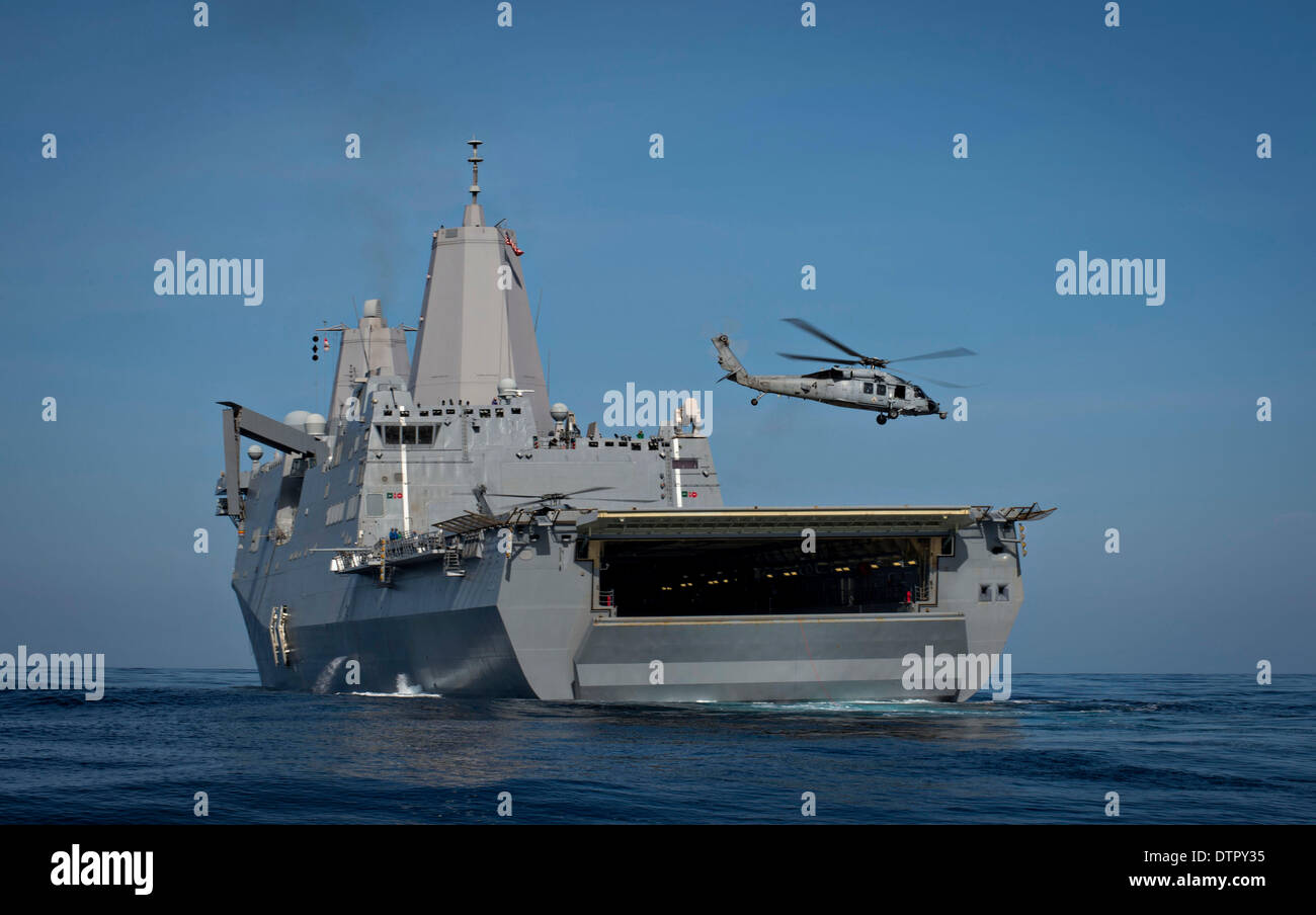 Un US Navy MH-60S Sea Hawk elicottero solleva dal trasporto anfibio dock nave USS San Diego durante la prima in mare la prova di recupero per la Orion modulo di equipaggio per la NASA il programma Orion Febbraio 20, 2014 nell'Oceano Pacifico. Foto Stock