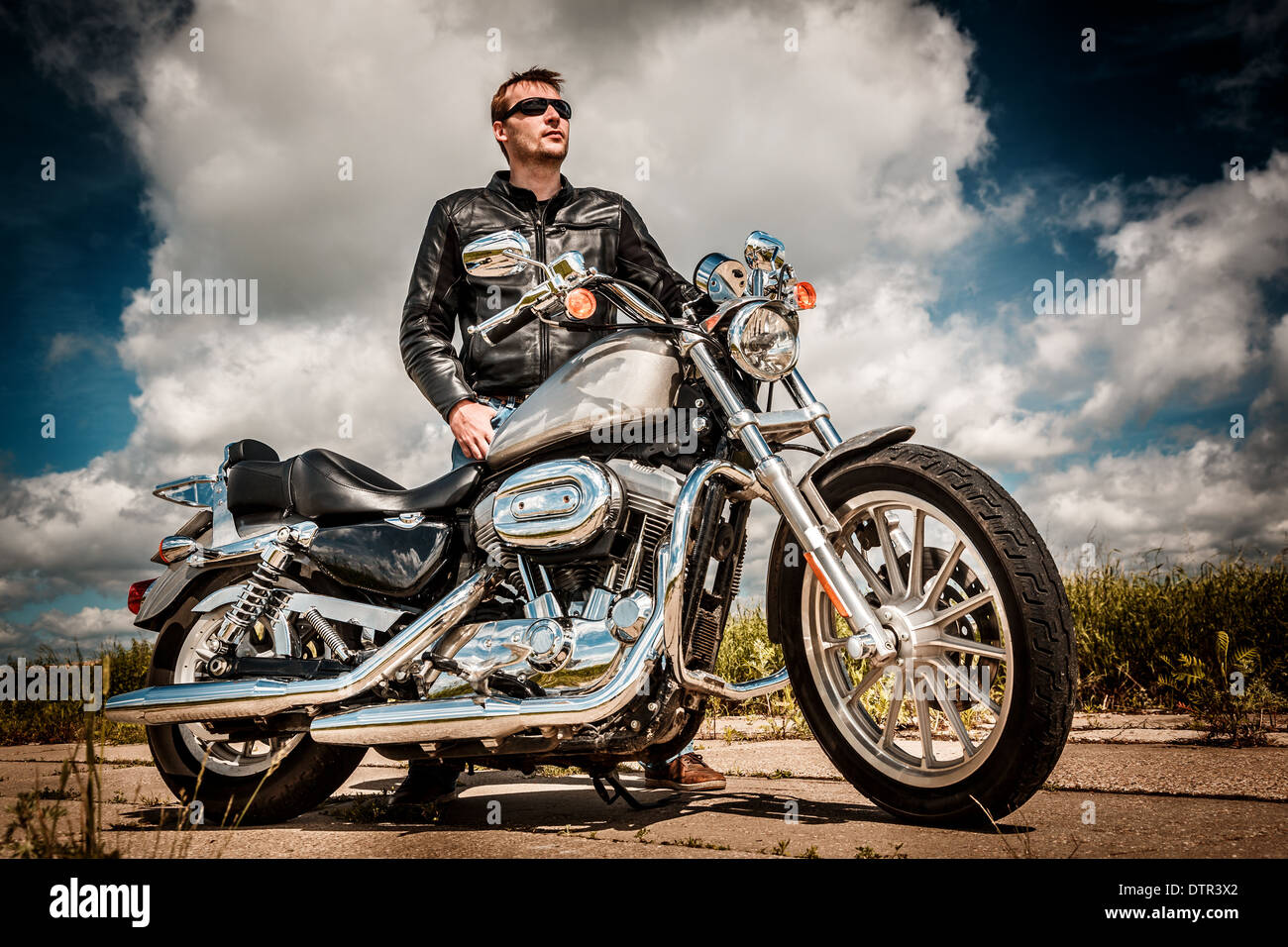 Biker in occhiali da sole e giacca di pelle sulla strada Foto Stock Biker in occhiali da sole e giacca di pelle sulla strada Foto Stock