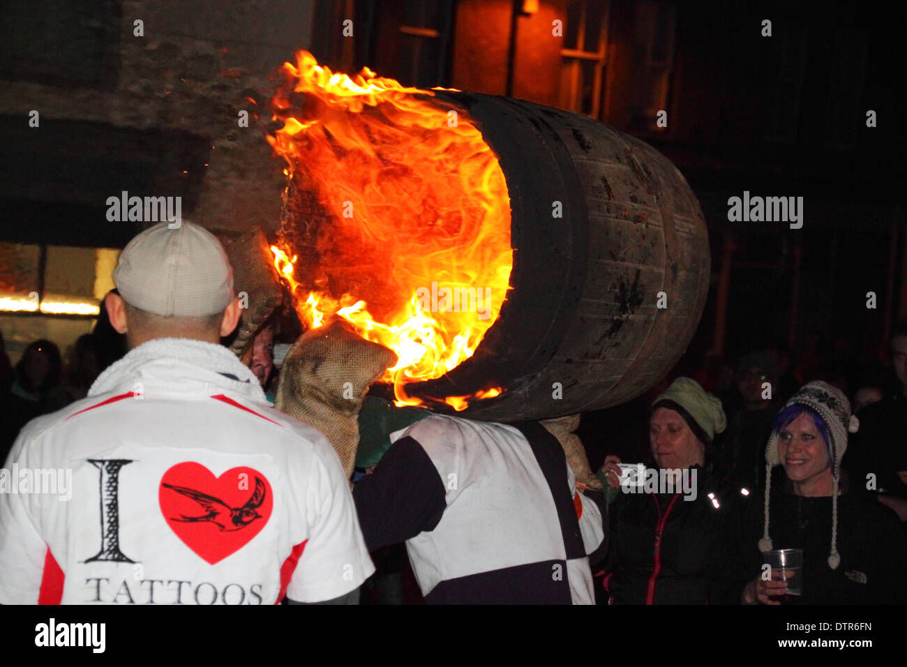 Un uomo che porta una fiammante tar barile sulle sue spalle. Foto Stock