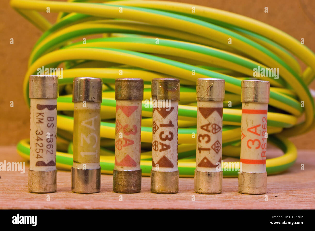 Fila di elettrodomestico fusibili con una bobina di filo di messa a terra il tubetto in background. Foto Stock