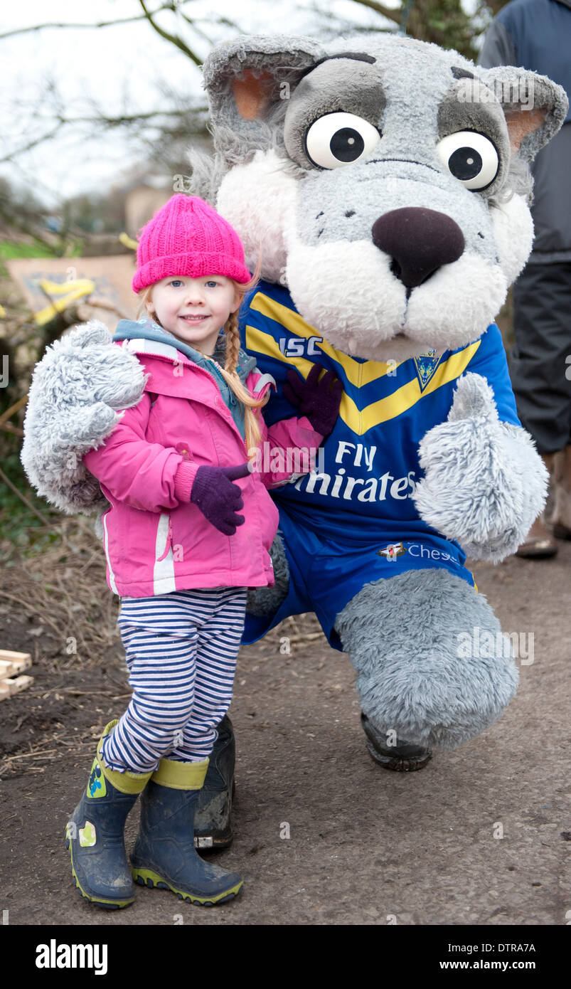 Barton Moss, Salford, Regno Unito. Domenica 23 febbraio 2014. Il Warrington Lupi Rugby League mascotte Wolfie '' in posa per una foto con una bambina a Barton Moss. Anti-fracking manifestanti su Barton Moss vicino al Manchester continuano la loro campagna per il terzo mese contro la perforazione esplorativa vicino all'IGas Barton sito. Gli attivisti temono che il procedimento di fratturazione idraulica potrebbe essere ambientalmente pericolosi e portare a l' avvelenamento delle fonti di approvvigionamento idrico e una contaminazione dell'atmosfera. Credito: Russell Hart/Alamy Live News. Foto Stock