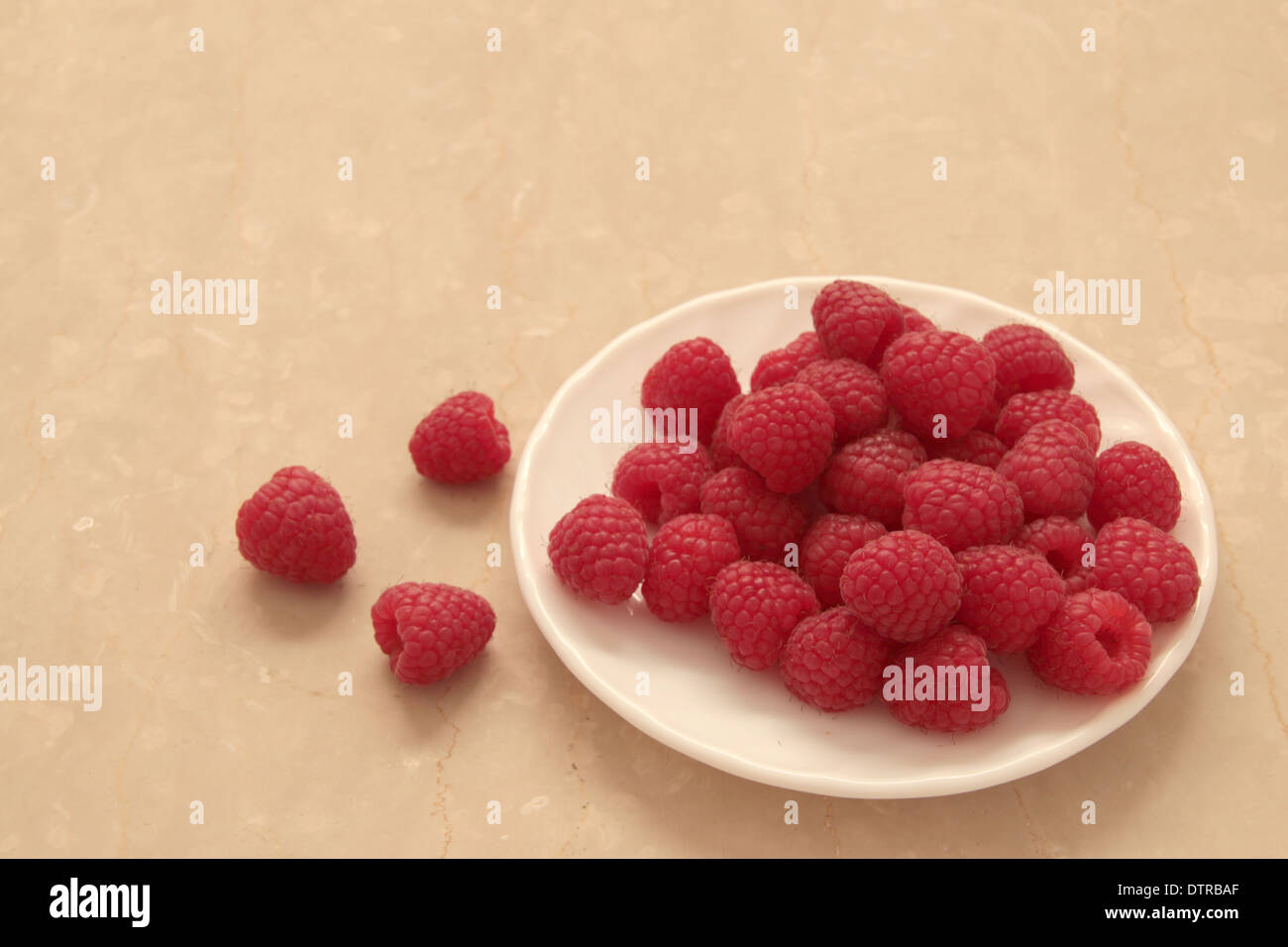 Lamponi su una piastra bianca con 3 raspe al lato sinistro di marmo di color crema sullo sfondo (8 di 11) Foto Stock
